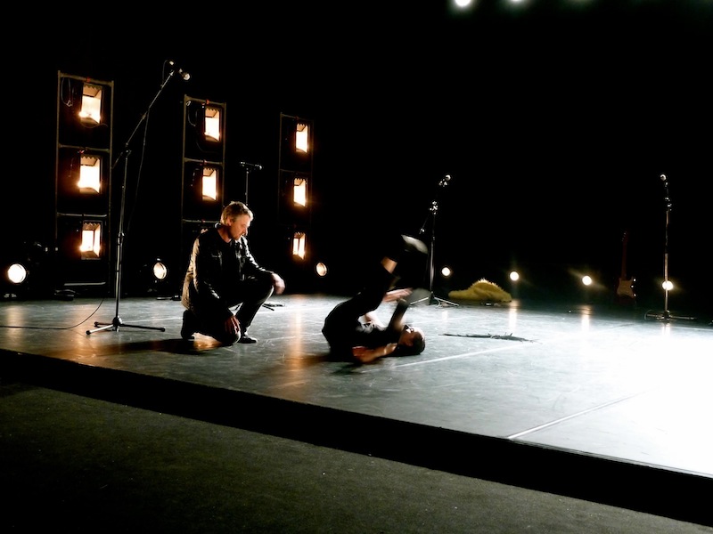 Damiano Fao crouches as he watches his collaborator Laura Simi perform a dance move on her back with her legs in the air